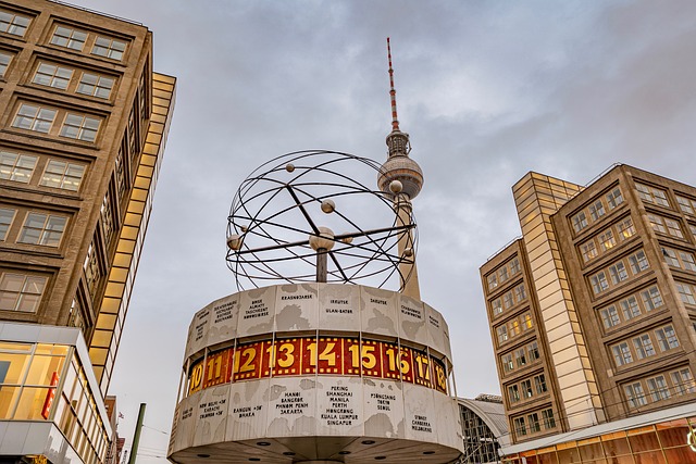 berlin The World Clock at Alexanderplatz in Berlin, Germany, with the iconic Berlin TV Tower in the background, surrounded by modern office buildings at dusk.